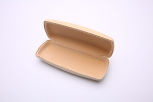 Glasögonfodral Beige, ett rektangulärt brunfärgat glasögonfodral, är öppet mot en vit bakgrund och avslöjar dess tomma interiör.
