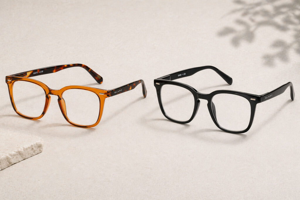 Två par läsglasögon visas på en ljusbeige yta. Det ena paret har ett sköldpaddsmönster och det andra paret är helt svart. Båda paren har fyrkantiga bågar och klara linser.